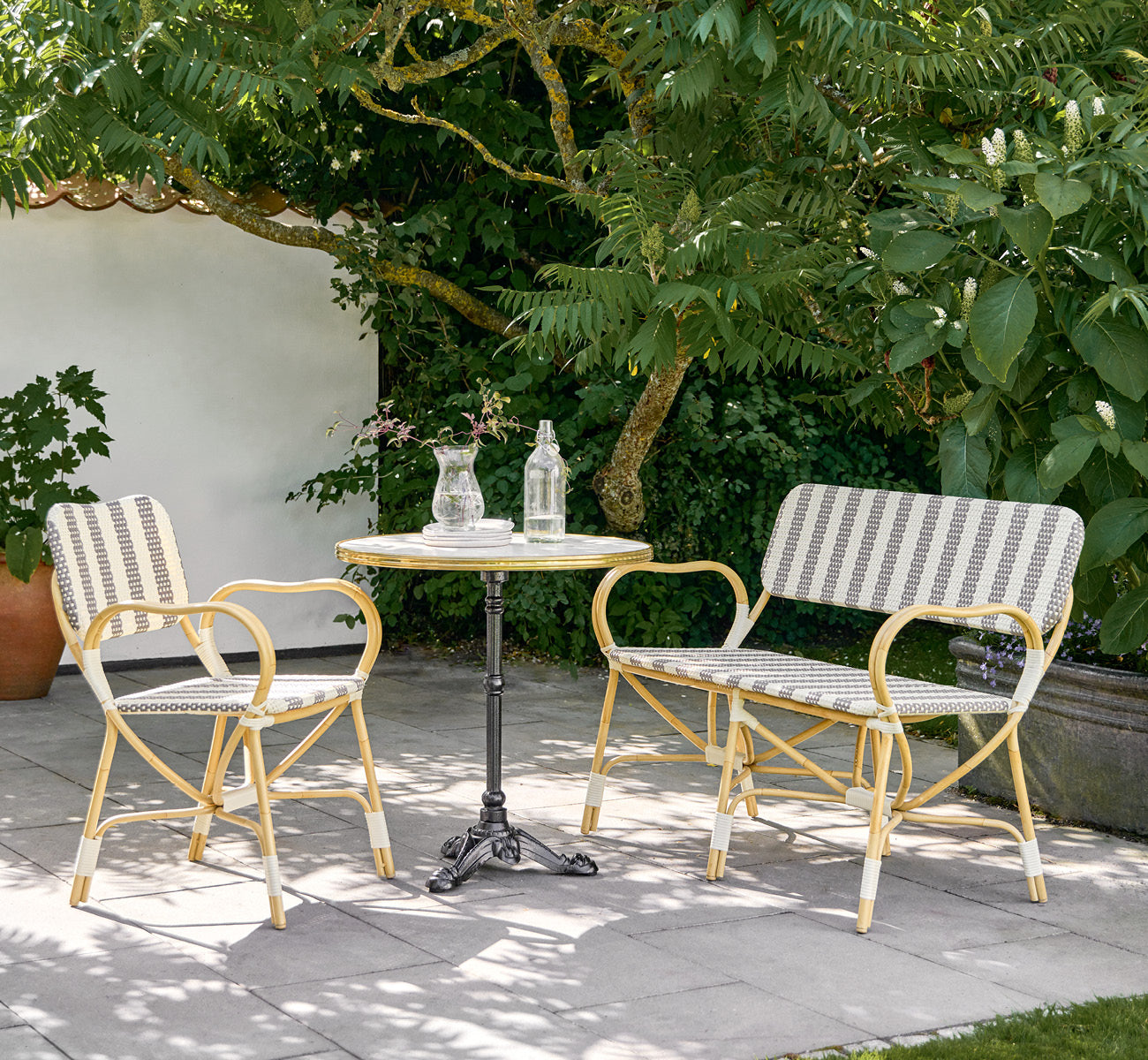 Dies ist ein Lifestyle-Bild von Bistro Exterior Stuhl in natural Aluminium ArtFibre, in einem Gartencafé im Freien mit einem Bistrotisch und.