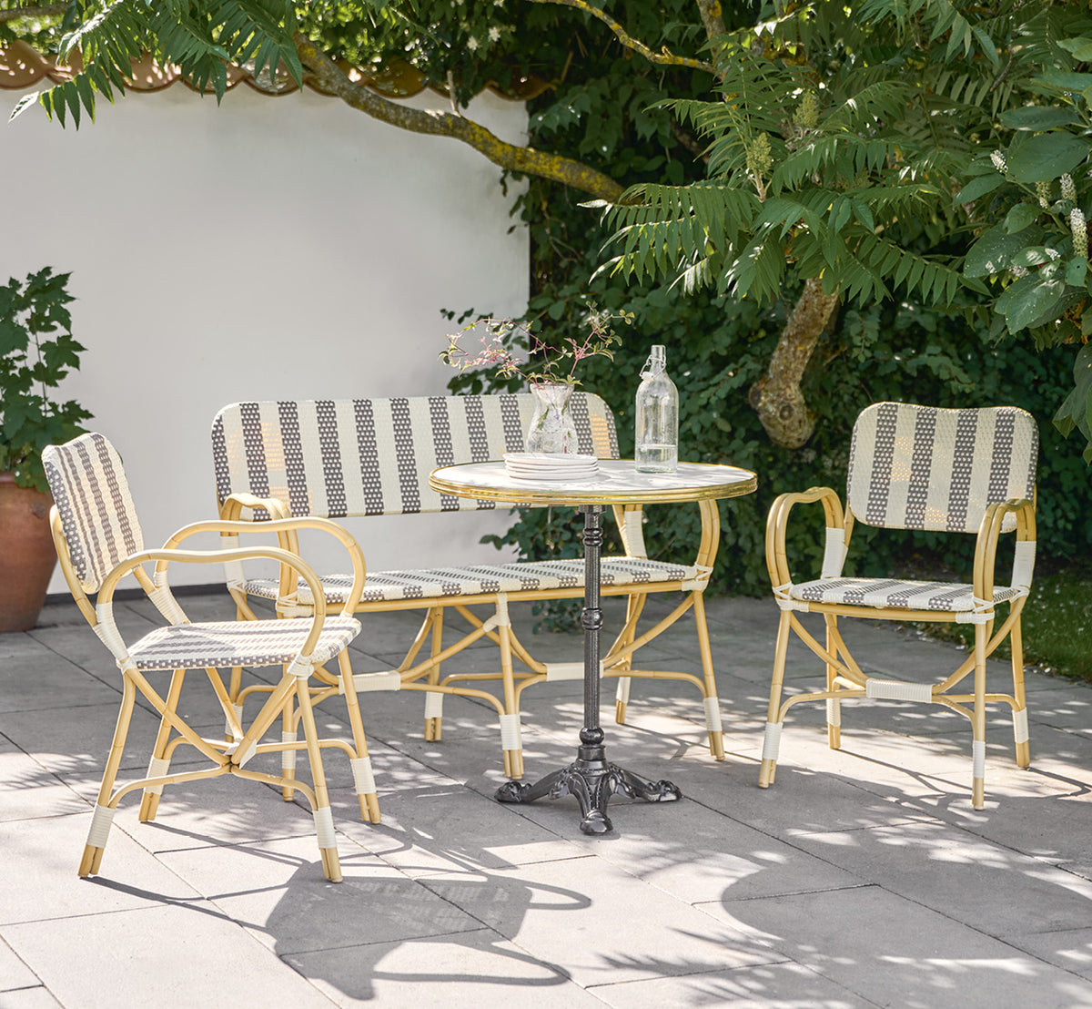 Dies ist ein Lifestyle-Bild von Bistro Exterior Stuhl in natural Aluminium ArtFibre, in einem Gartencafé im Freien mit einem Bistrotisch und.