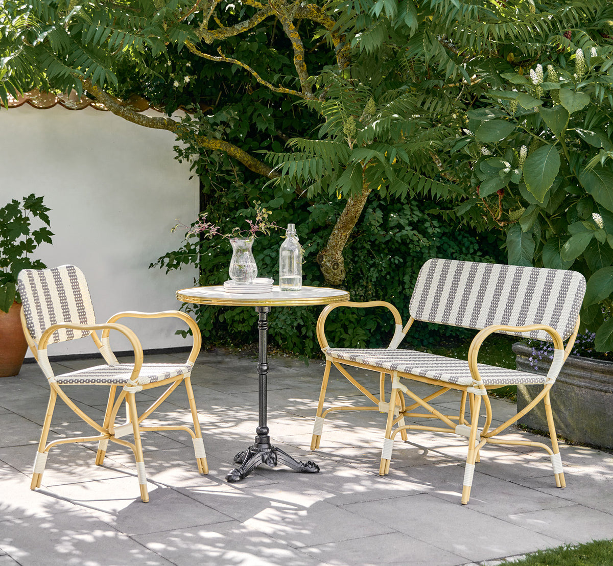 Dies ist ein Lifestyle-Bild von Bistro Exterior Stuhl in natural Aluminium ArtFibre, in einem Gartencafé im Freien mit einem Bistrotisch und.