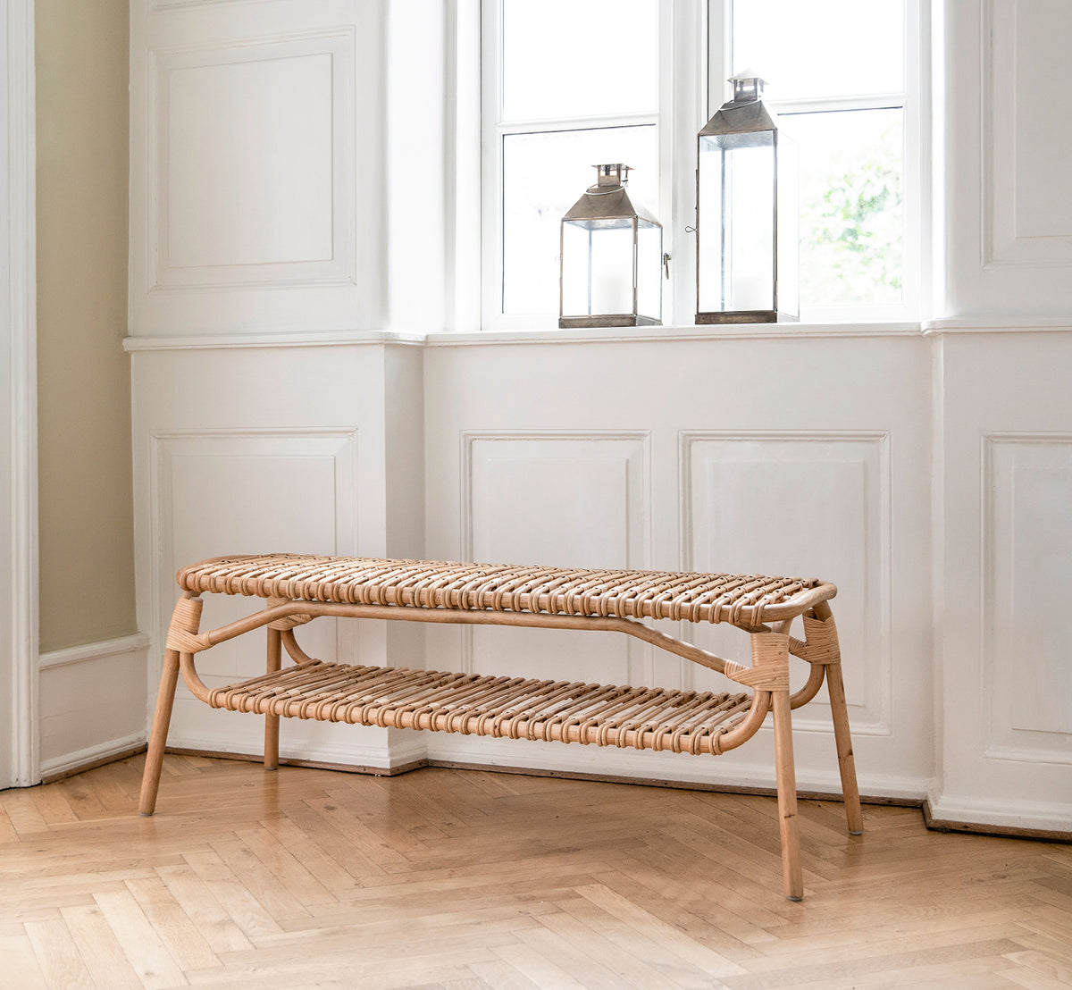 Dies ist ein Lifestyle-Bild von Machiya Bench in natural skin on rattan. In einem hellen Interieur gestylt.