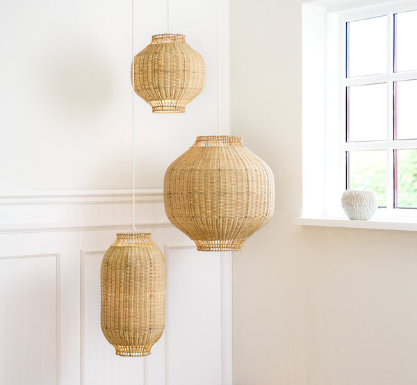 Dies ist ein Lifestyle-Bild von Tomos Lampenschirm in natural core weave rattan frame. Mit anderen Pendelgrößen in einem hellen vertäfelten Raum hängend.