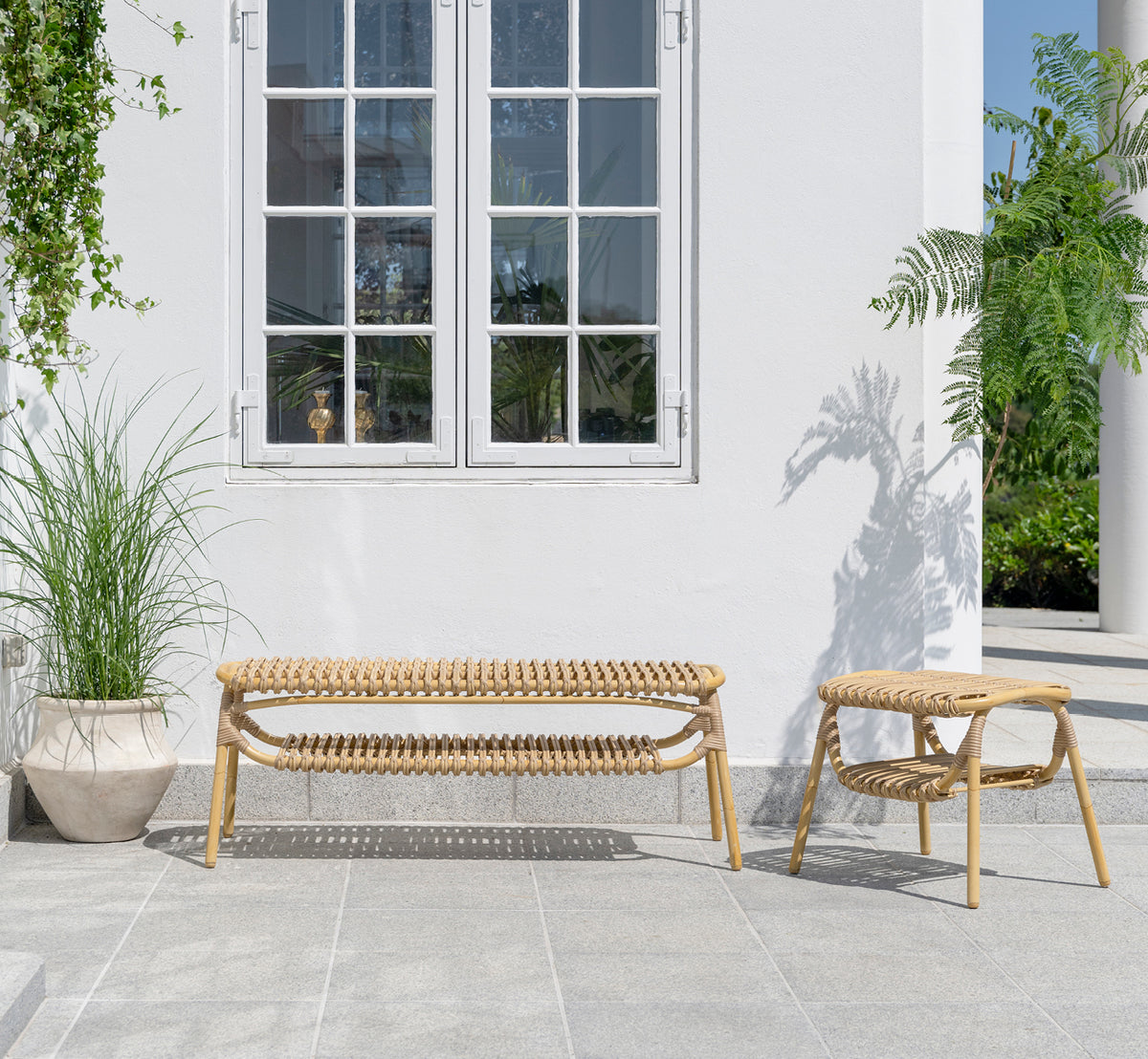 Dies ist ein Lifestyle-Bild von Machiya Außenbank in natural aluminium artfibre. Weiße Terrasse mit Außenhocker und grünen Pflanzen.