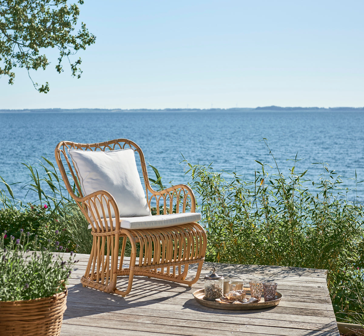 Dies ist ein Lifestyle-Bild von Tulip Außen-Lounge-Sessel in natural aluminium artfibre. In einem hellen Interieur gestylt.