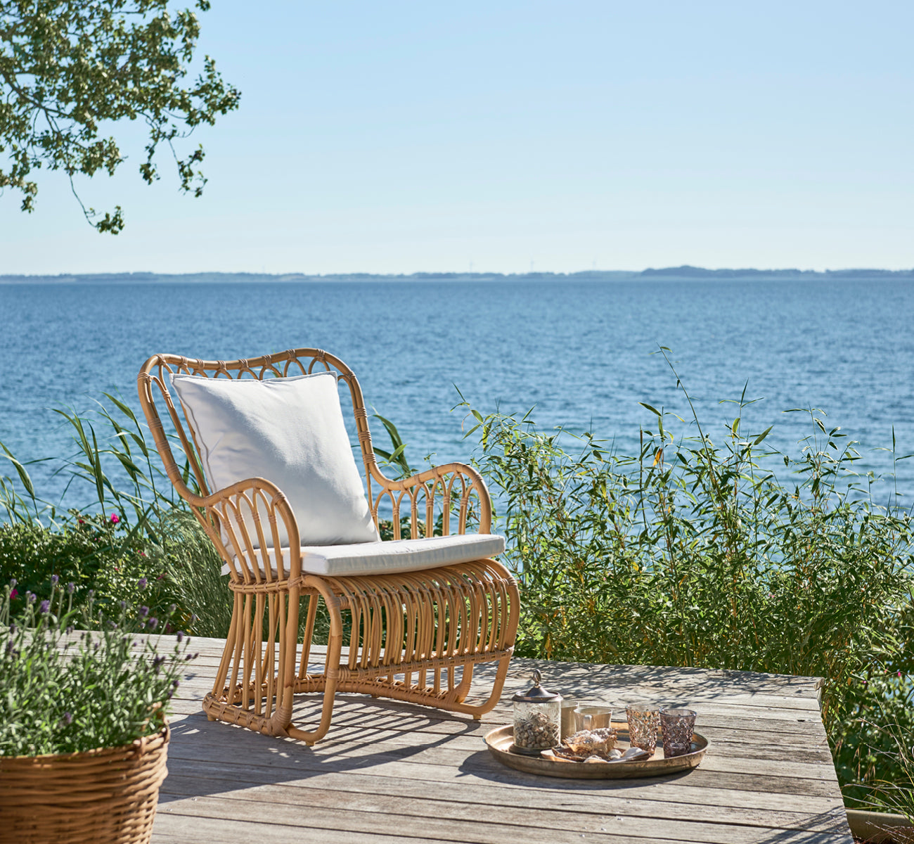Dies ist ein Lifestyle-Bild von Tulip Außen-Lounge-Sessel in natural aluminium artfibre. In einem hellen Interieur gestylt.