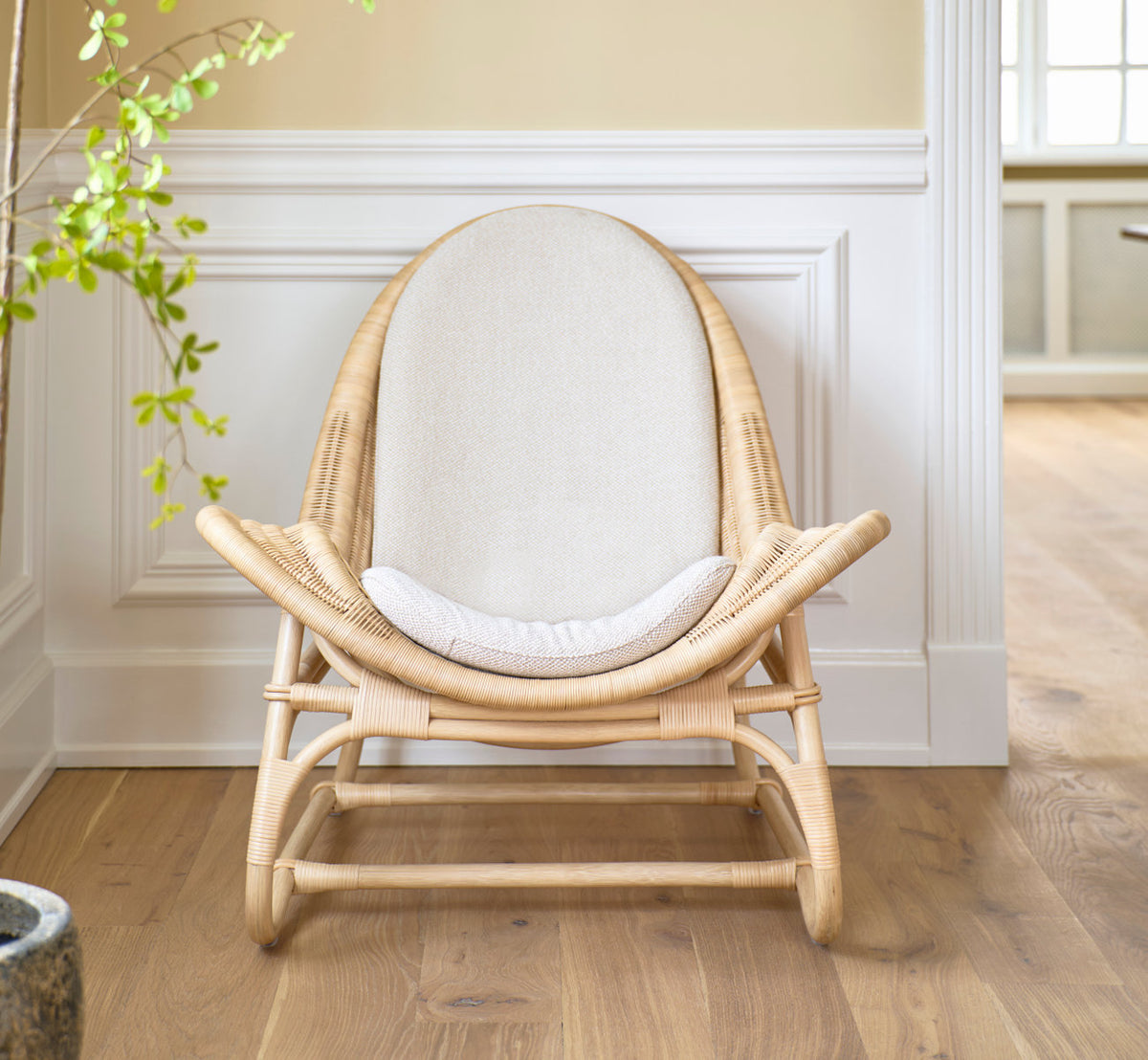 Dies ist ein Lifestyle-Bild von Pacifique Lounge-Sessel in natural core weave rattan frame. Mit Leinenkissen vor weißen Paneelen.