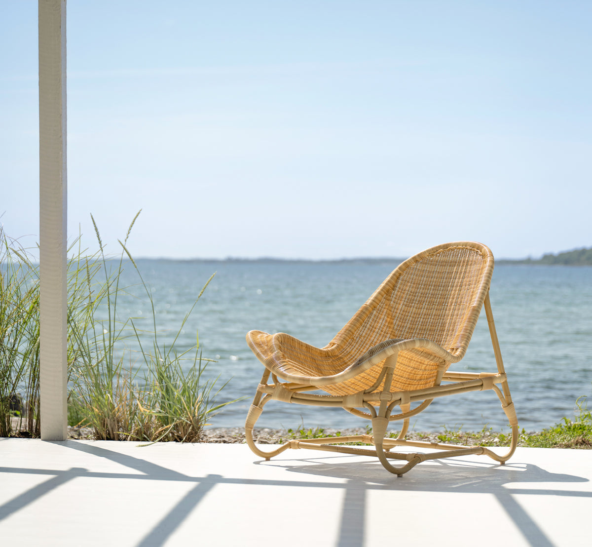 Dies ist ein Lifestyle-Bild von Pacifique Außen-Lounge-Sessel in natural core weave artfibre aluminium. In einem hellen Interieur gestylt.