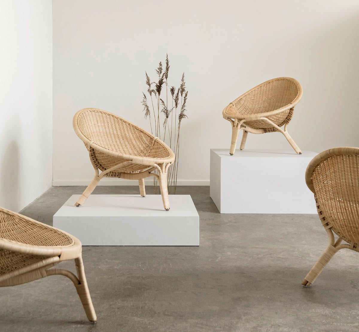 Dies ist ein Lifestyle-Bild von Rana Lounge-Sessel in natural core weave rattan frame. Allein in einem Raum mit vergoldeter Vertäfelung und Parkettboden stehend.