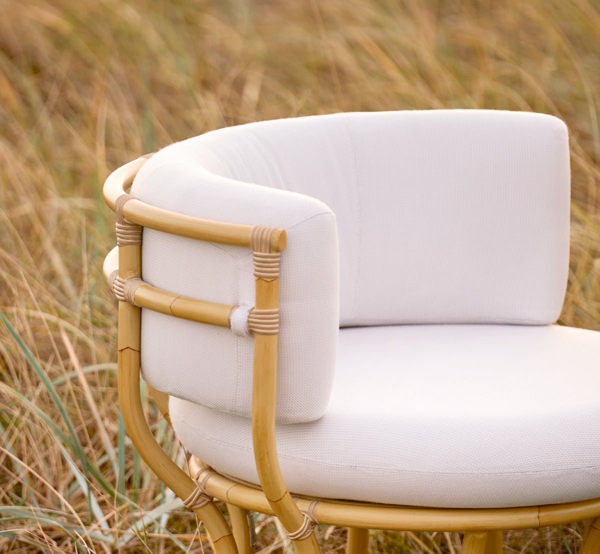 Dies ist ein Lifestyle-Bild von Coco Außen-Lounge-Sessel in natural Aluminium ArtFibre, auf einer offenen Küstenterrasse bei Sonnenuntergang mit.