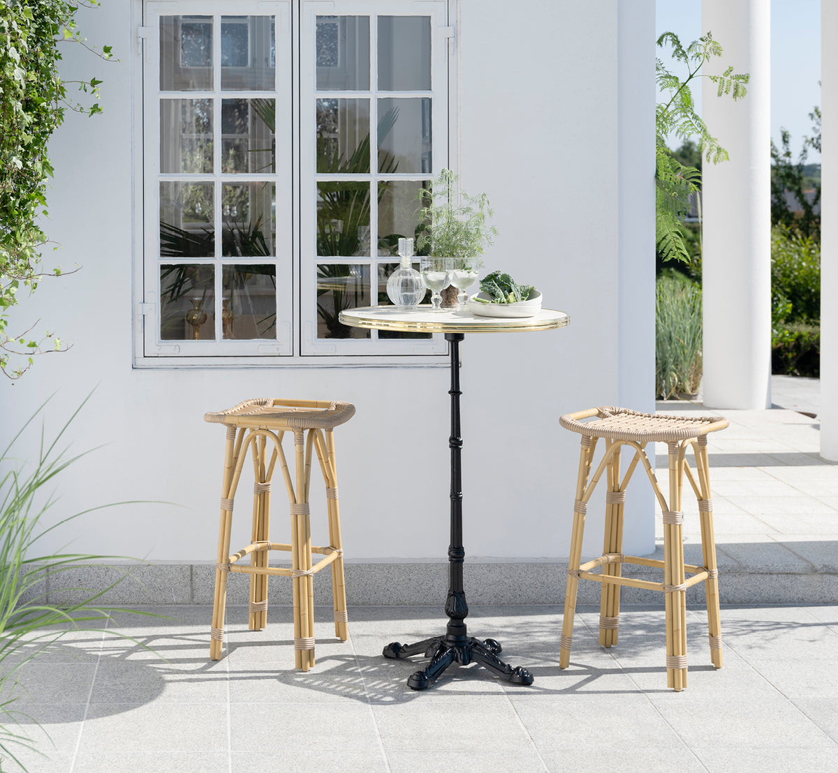 Dies ist ein Lifestyle-Bild von Salsa Außen-Barhocker in natural aluminium artfibre. Elegante Terrasse mit Bartisch und grünen Pflanzen.