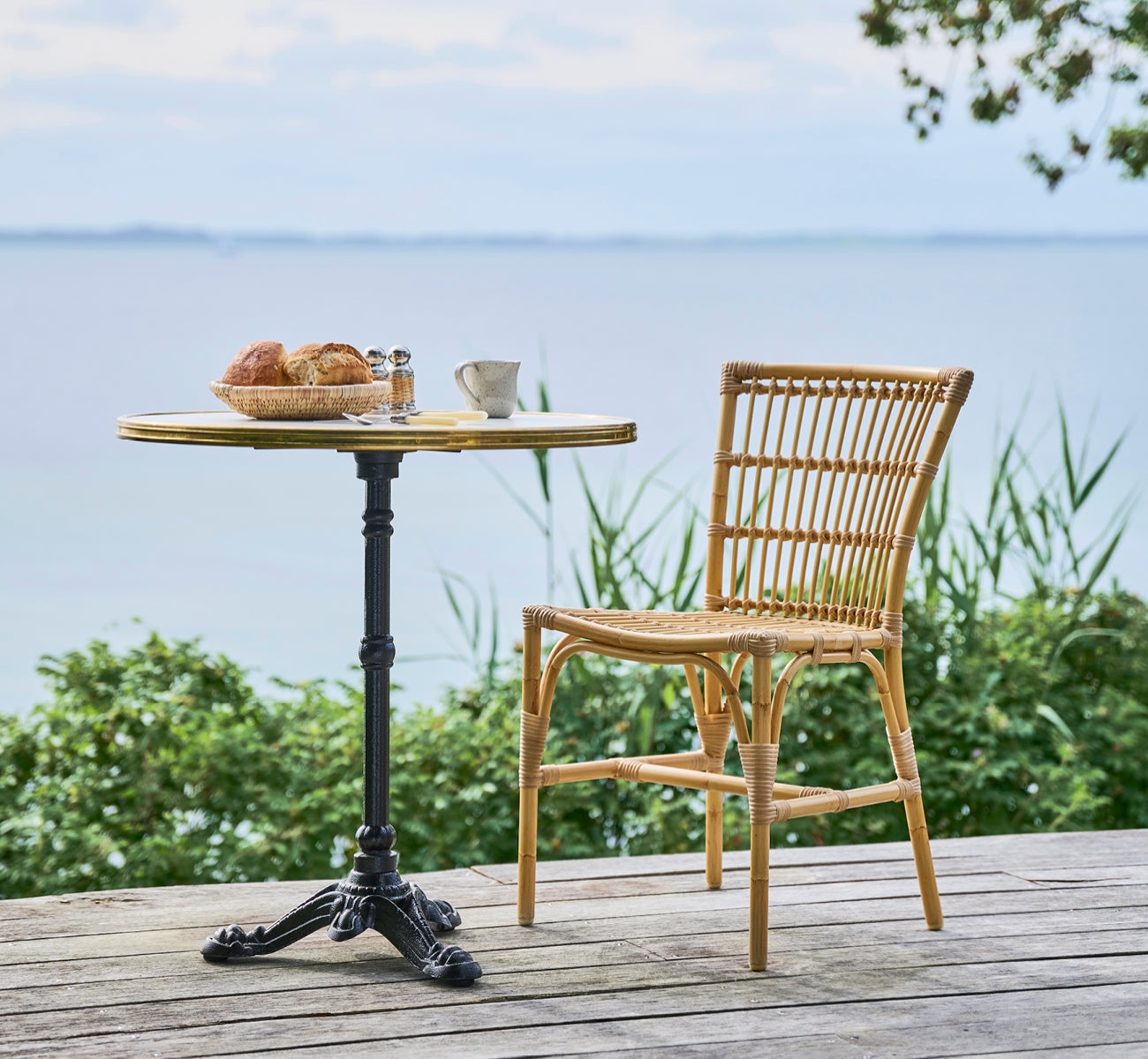 Dies ist ein Lifestyle-Bild von Elisabeth Außen-Esszimmerstuhl in natural Aluminium ArtFibre, auf einem Holzdeck mit einem Bistro-Frühstückstisch mit.