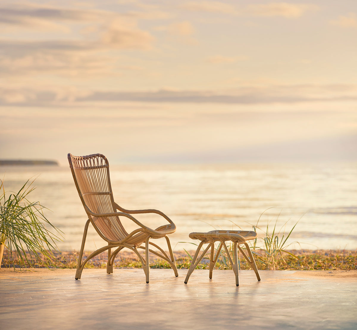Dies ist ein Lifestyle-Bild von Monet Exterior Lounge Chair i antique aluminium artfibre. In einem Strandpavillon mit weißen Vorhängen.