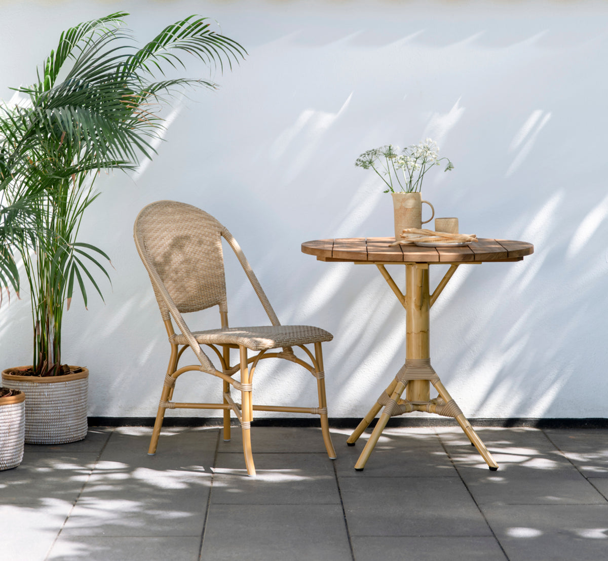 Dies ist ein Lifestyle-Bild von Nicole Cáfe Table | Teak Ø80 cm in natural aluminium artfibre. In einem hellen Interieur gestylt.