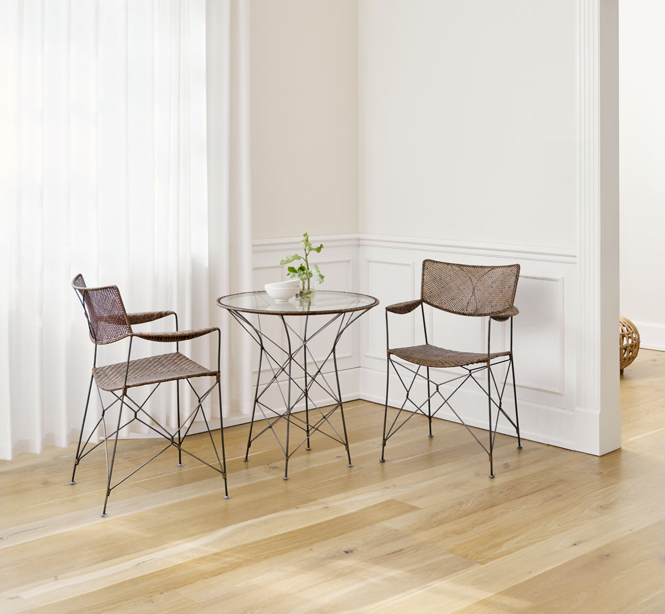 Dies ist ein Lifestyle-Bild von Rap Esszimmerstuhl in hazelnut rattan iron frame, in einem hellen Interieur mit weißen Wandpaneelen und.