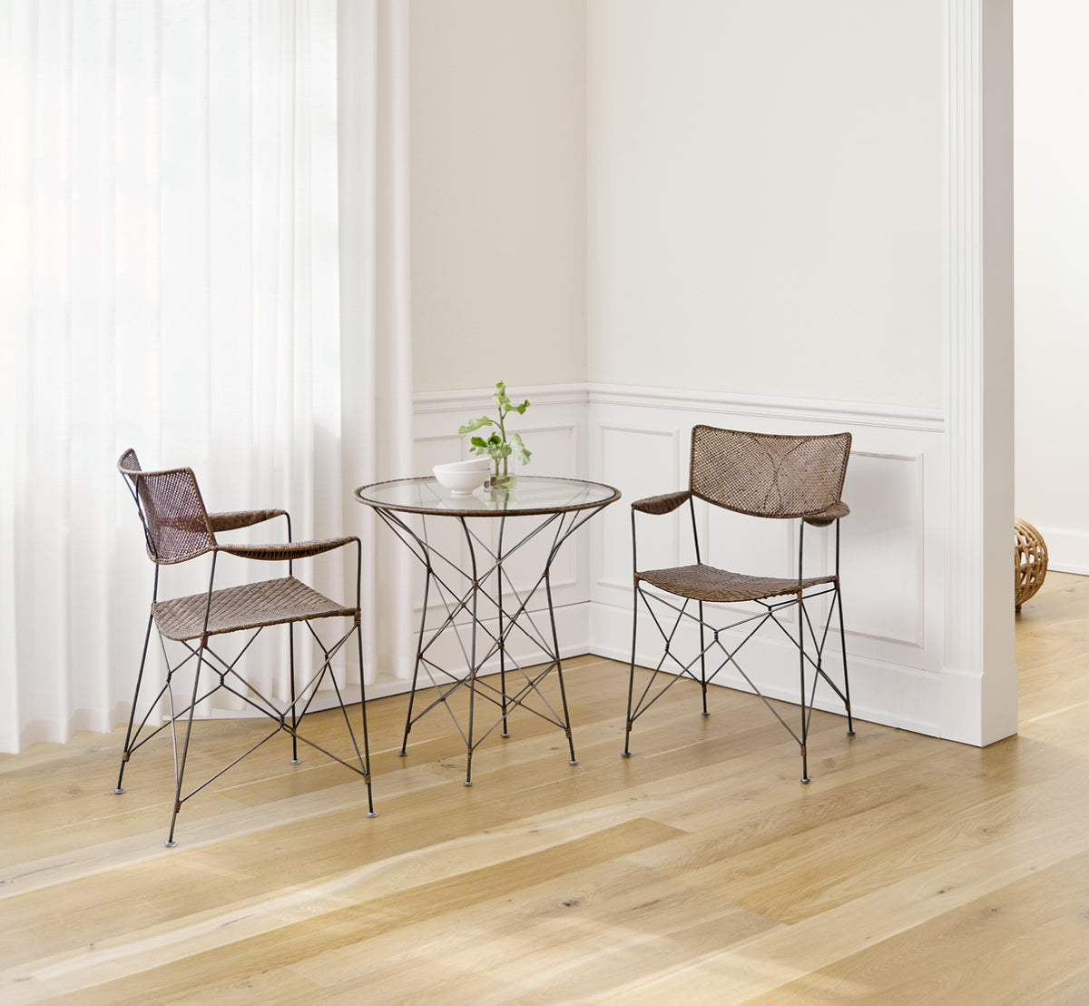 Dies ist ein Lifestyle-Bild von Rap Esszimmerstuhl in hazelnut rattan iron frame, in einem hellen Interieur mit weißen Wandpaneelen und.