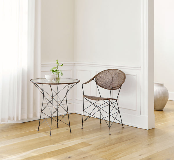 Dies ist ein Lifestyle-Bild von Funky Esszimmerstuhl in hazelnut rattan iron frame, in einem hellen Interieur mit weißen Wandpaneelen und.