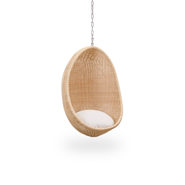 Seitenansicht des Hanging Egg Junior, der Kinderversion des ikonischen Hängesessels, entworfen von Nanna und Jørgen Ditzel. Der runde Hängesessel ist vollständig aus hochwertigem indonesischem Rattan geflochten und hängt an einer Metallkette.