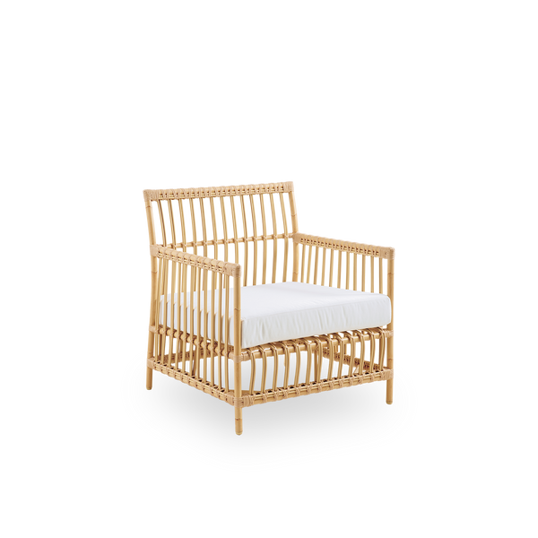 Seitenansicht des Caroline Outdoor-Lounge-Stuhls in der Farbe Natural, handbemalt, um wie Rattan auszusehen. Der Rahmen des Stuhls besteht aus Aluminium mit eleganten ArtFibre-Details. Das Design ist minimalistisch und elegant.